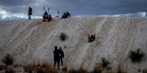 Kids Enjoy Sliding Down The Slope In White Sands National Monument, NM