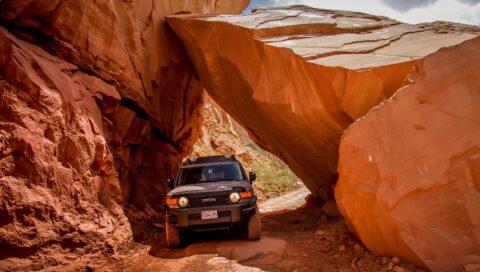 Driving Through Tight Passage Under Big Boulder In Long Canyon, Moab, UT