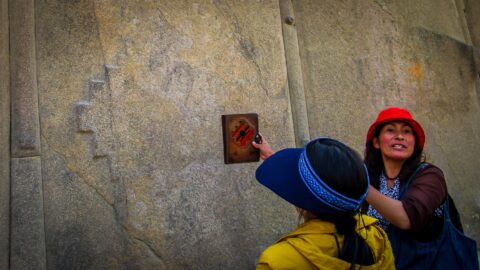 Guide Explains Inca Cross Carved In The Stone Wall Of  Ollantaytambo Ruins in the Sacred Valley,  Peru